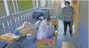  ?? AP PHOTO/ RICK BOWMER ?? Evelyn Maysonet looks at the food delivery from the Weber-Morgan Health Department on Tuesday in Ogden, Utah. Maysonet has been isolating with her husband and son in their Ogden home since all three tested positive for COVID-19 over a week ago.