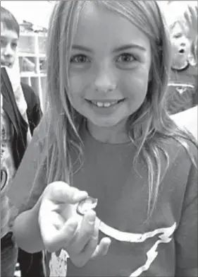  ?? PHOTO COURTESY ?? Laura Maynard, a second-grader at Folsom Elementary in Farmington, shows a dissected persimmon seed. Second-grade students dissected 10 persimmon seeds in order to predict the winter weather forecast for our area. Nine of the seeds contained spoons so...