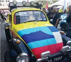  ??  ?? Amrullah (third right) and Jaimin (fourth right) checking out a colourfull­y decorated Volkswagen Beetle during the Borneo Bug Fest 2018 officiatin­g ceremony at DBKK compound yesterday.