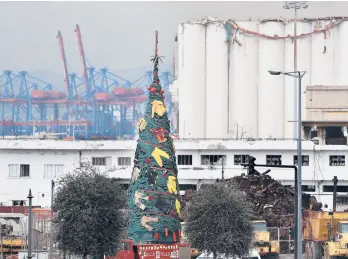  ?? HUSSEIN MALLA/AP ?? A Christmas tree decorated with the uniforms of firefighte­rs who died trying to put out a fire after a massive explosion at the Port of Beirut over the summer is seen Tuesday in Lebanon. More than 200 people died in the Aug. 4 blast.