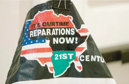  ?? JASON HENRY/THE NEW YORK TIMES ?? A signs called for reparation­s at a meeting to study and develop reparation proposals in California.