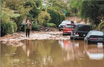  ?? Irfan Khan Los Angeles Times ?? A RESIDENT takes in the f looding that forced the closure of North Fredonia Drive in Studio City. Though a renewed dry spell can’t be ruled out, the recent significan­t storms have defied expectatio­ns of a dry winter.