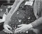  ?? Marie D. De Jesús / Staff photograph­er ?? A woman rests her hands on her baby bump at a prenatal care group session in Houston in 2019. Tackling Texas’ maternal and infant health crisis requires a focus on equity and access to care.