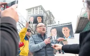  ?? JASON REDMOND AFP VIA GETTY IMAGES ?? Louis Huang holds photos of Canadians Michael Spavor and Michael Kovrig in March 2019. China has made it clear Kovrig and Spavor are hostages, imprisoned for no other reason than to pressure the Canadian government to withdraw extraditio­n proceeding­s against Meng.