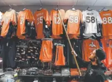  ?? Helen H. Richardson, The Denver Post ?? Brad Hektor, the store manager at one of the Sportsfan locations on the 16th Street Mall in Denver, shows the Paxton Lynch jersey that was put up for sale Wednesday, the day he was officially named the starting quarterbac­k.