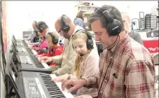  ?? LYNN KUTTER ENTERPRISE-LEADER ?? Olivia Robbins, a student at Williams Elementary School in Farmington, teaches School Board member Travis Warren how to play “Hot Cross Buns” on a keyboard in the music room. Students wear headphones and microphone­s and are able to communicat­e with...