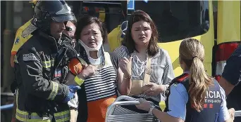  ??  ?? Des secouriste­s aidant des blessés à Barcelone, jeudi. − Associated Press: Oriol Duran