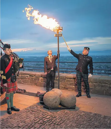  ?? ?? A beacon being lit at Edinburgh Castle, above. Far left, the Queen switches on lights at Windsor Castle, and left, soldiers parade along The Mall