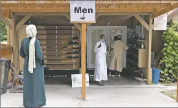  ?? (AP/Karen Ducey) ?? Shukri Olow (left) gets a thumbs-up as she greets worshipper­s outside the Islamic Center of Kent in Kent, Wash., south of Seattle.