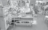  ??  ?? Patients and their kin rest in beds surrounded by floodwater­s during heavy rain in Nalanda Medical College, Patna on Monday.