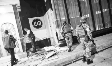  ?? — AFP photo ?? Members of the Mexican army look at damage caused by an earthquake in the Port of Veracuz.