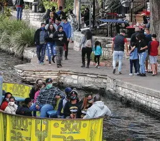  ??  ?? Narrow walkways along the River Walk often make 6 feet of social distancing impossible. Still, some visitors stroll maskless.