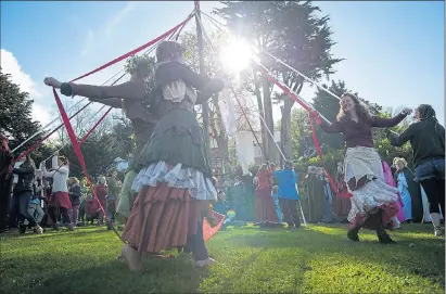  ??  ?? A glimpse of sun for those taking part in the traditiona­l maypole dance at Chalice Well in Glastonbur­y, Somerset