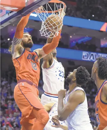  ?? MICHAEL PEREZ / AP ?? Oklahoma City Thunder's Steven Adams (12) dunks the ball over Philadelph­ia 76ers' Jimmy Butler (23) andf Joel Embiid during the first half.