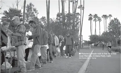  ?? AP Photo/Jae C. Hong ?? Homeless people wait in line for a free meal Thursday in Dana Point, Calif.