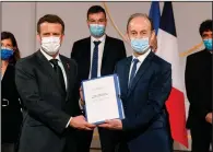  ?? (AP/Ludovic Marin) ?? Vincent Duclert (right), head of the French commission that reviewed France’s role in the genocide in Rwanda, gives the commission report to President Emmanuel Macron on Friday at Elysee Palace in Paris.