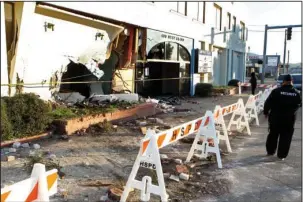  ?? The Sentinel-Record/Richard Rasmussen ?? WRECK AFTERMATH: A security guard walks past 600 W. Grand Ave. Tuesday morning after an allegedly stolen Dodge Challenger crashed into the side of the building while fleeing from Hot Springs police. The driver, identified as Noah Christophe­r Merritt,...