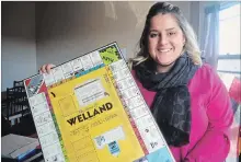  ?? MIKE ZETTEL NIAGARA THIS WEEK ?? Amanda MacDonald holds up a vintage copy of a Monopoly-inspired board game featuring Welland landmarks and businesses.