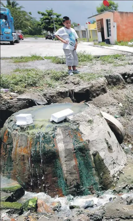  ??  ?? ADELA BLANCO uses a broom to retrieve a basketball in a pit of sewage near her home in Colinas de Santa Fe in Veracruz, Mexico. At the developmen­t, which was partially built on a wetlands area, rainwater and raw sewage have backed up into homes and...