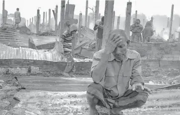  ?? MOHAMMED FAISAL/AP ?? New blow for refugees: A Rohingya refugee sits by charred remains after a fire broke out Thursday at a camp in southern Bangladesh. Officials said more than 550 homes sheltering about 3,500 people were partially or totally destroyed, but no casualties were reported. About 700,000 Rohingya fled to camps from Myanmar after August 2017.