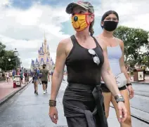  ?? JOE BURBANK
Orlando Sentinel/TNS ?? Guests wear masks as required on the re-opening day of the Magic Kingdom in Lake Buena Vista on July 11.