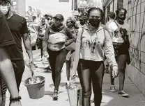  ??  ?? People gather to clean a Los Angeles neighborho­od after riots last week. The neighborho­od is the unit of change, because residents know how to lift them. They just need the resources.