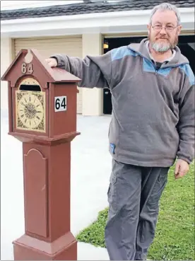  ??  ?? Mechanical maestro: Clock restorer Doug Tucker stands next to his handmade grandfathe­r clock letterbox, which is permanentl­y set at 3 o’clock, indicating his closing time to customers.