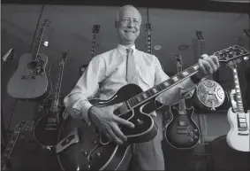  ?? TRIBUNE NEWS SERVICE ?? Gibson chief executive Henry Juszkiewic­z holds a Gibson guitar in front of a wall of guitars outside of his office at the Gibson Guitar corporate offices in Nashville, Tennessee in 2011.