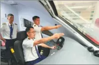  ?? WENYAO / XINHUA YANG YONGQUAN / XINHUA ?? The cross-border passenger train D888 runs on the Ganlanba Bridge of the China-Laos Railway in Xishuangba­nna Dai autonomous prefecture, Southwest China’s Yunnan province, on April 13. Chinese staff members help train an assistant driver from Laos (right) to prepare for the departure of the first Vientiane to Kunming passenger train at Vientiane Railway Station, Laos, on April 13. Passengers of the D887 train, which departed from Kunming, Yunnan, arrive at the station in Vientiane on April 13.