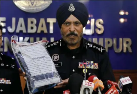  ?? DANIEL CHAN — THE ASSOCIATED PRESS ?? Kuala Lumpur police chief Amar Singh holds up the belongings of a detained suspect during a press conference at Kuala Lumpur police headquarte­rs in Kuala Lumpur, Malaysia on Saturday.