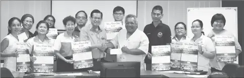  ??  ?? Musa presenting the cheque for the amount to Lee (centre) in the presence of Judy (sixth left), Iqbal (fourth right) and other committee members.