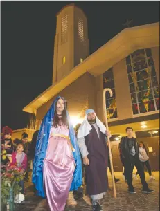  ??  ?? Mary, played by Clarisa Carrillo, the religious education secretary at St. Anne’s school, and Joseph, played by Ray Naylor, director of facilities, walk between inns during Las Posadas at St. Anne’s Catholic Church in Lodi on Wednesday.