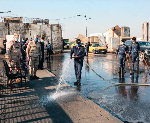  ??  ?? Iraqi security forces clean the Jumhuriyah bridge leading from Baghdad’s central Tahrir Square to the highly fortified Green Zone, as it reopens on Saturday. AFP