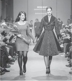  ?? GENEVIèVE GIGUèRE ?? Nicole Boyer walks down the runway in Montreal with a model who is wearing her award- winning coat. She was inspired by ’ 40s film stars such as Myrna Loy.
