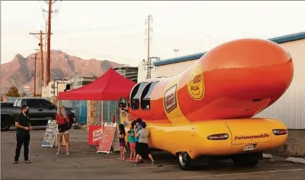  ?? CASSIDY ARAIZA/THE NEW YORK TIMES ?? Molly Swindall, an Oscar Mayer Hotdogger, speaks to children visiting the Oscar Mayer Wienermobi­le at Bob-o’s Family Fun Center in El Paso, Texas, in September. Piloting the most recognizab­le vehicle in America for a year isn’t an easy gig to land.