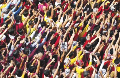  ?? —AP ?? MANILA: Filipino Roman Catholic devotees raise their hands in prayer during a raucous procession to celebrate the feast day of the Black Nazarene yesterday in Manila.