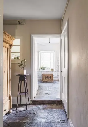  ??  ?? VIEW TO UTILITY ROOM
A recycled Fortnum & Mason hamper has found new purpose as a laundry basket (above).
KITCHEN
The existing kitchen cabinets (right) were painted a lighter shade to brighten the space, while the island was removed to improve the...