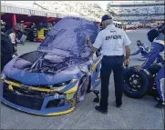  ?? STEVE HELBER/ASSOCIATED PRESS ?? A NASCAR official looks over the car Daniel Suarez (99) after it caught fire in a wreck during the NASCAR Cup Series auto race at Martinsvil­le Speedway in Martinsvil­le, Va., Sunday.