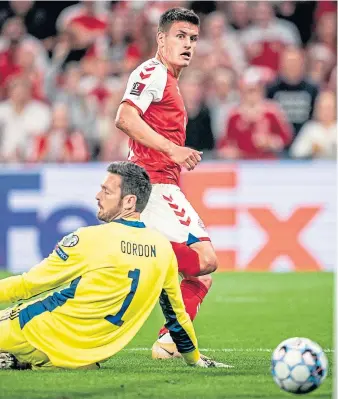  ??  ?? Joakim Mahle slots Denmark’s second goal past Scotland’s Craig Gordon.