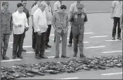  ?? AP/AARON FAVILA ?? Philippine President Rodrigo Duterte (center) on Wednesday in Manila takes a look at weapons confiscate­d during a siege by militants in the city of Marawi.