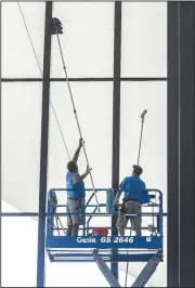  ?? AP/The Messenger-Inquirer/GREG EANS ?? Tad Bunker (left) and Derek Masterson with Clear Solutions in Evansville, Ky., clean the inside windows at the Owensboro Convention Center on Tuesday.