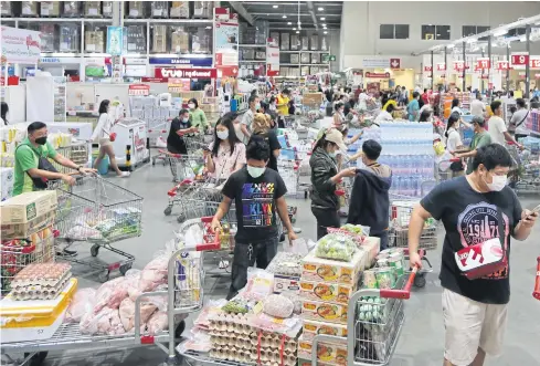  ??  ?? STOCKING UP: Shoppers form long queues at the Makro wholesale store in Samut Prakan after City Hall yesterday issued an order closing shopping malls and markets in Bangkok and adjacent provinces except those selling food and essential consumer goods for three weeks in an effort to slow the spread of Covid-19.