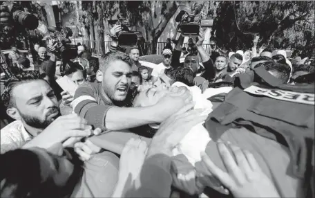  ?? Mahmud Hams AFP/Getty Images ?? MOURNERS carry the body of Yasser Murtaja, who was filming protests Friday in an area engulfed in thick smoke when he was shot.