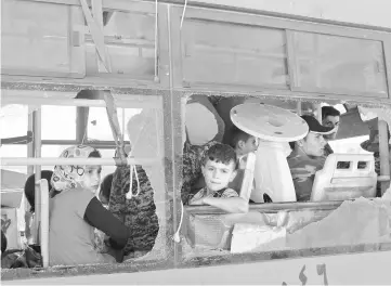  ??  ?? Evacuated Syrians from the area of Fuaa and Kafraya in the Idlib province, look out of a broken bus window as it passes the al-Eis crossing south of Aleppo during the evacuation of several thousand residents from the two pro-regime towns in northern Syria. — AFP photo