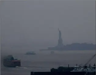  ?? (AP/Julie Jacobson) ?? The Staten Island Ferry departs Tuesday from the Manhattan terminal through a haze of smoke with the Statue of Liberty barely visible in New York. Wildfires in the American West, including one burning in Oregon that’s currently the largest in the U.S., are creating hazy skies as far away as New York as the massive infernos spew smoke and ash into the air in columns up to 6 miles high.