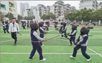  ?? HUANG LERAN / FOR CHINA DAILY ?? Students practice swordplay at Yingbinlu Primary School in the Jinniu district of Chengdu, Sichuan province, last week while sports teacher Zeng Ke looks on.