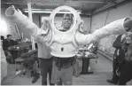  ?? Associated Press ?? n Andrzej Stewart puts on a new space suit at the Rhode Island School of Design in Providence, R.I. The white suit is made of heavy-duty nylon fabric; carbon fiber that forms a hard shell for the upper torso area; and foam that replicates the...