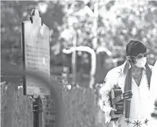  ?? ARIEL COBBERT/ THE COMMERCIAL APPEAL ?? A man dressed as Elvis Presley wearing a face mask stands outside the mansion at Graceland in Memphis on Thursday. Graceland reopened for the first time since closing March 20.