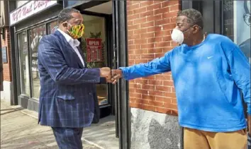  ?? Steve Mellon/Post-Gazette ?? Pittsburgh mayoral candidate Ed Gainey, left, gives a fist bump to Arnold Wilson, 71, while walking along Penn Avenue in East Liberty on March 24.