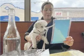  ?? AP PHOTOS ?? RIGHT: Ilana Minkoff checks out the menu with her dog JoJo Wigglebutt at a restaurant in San Francisco.